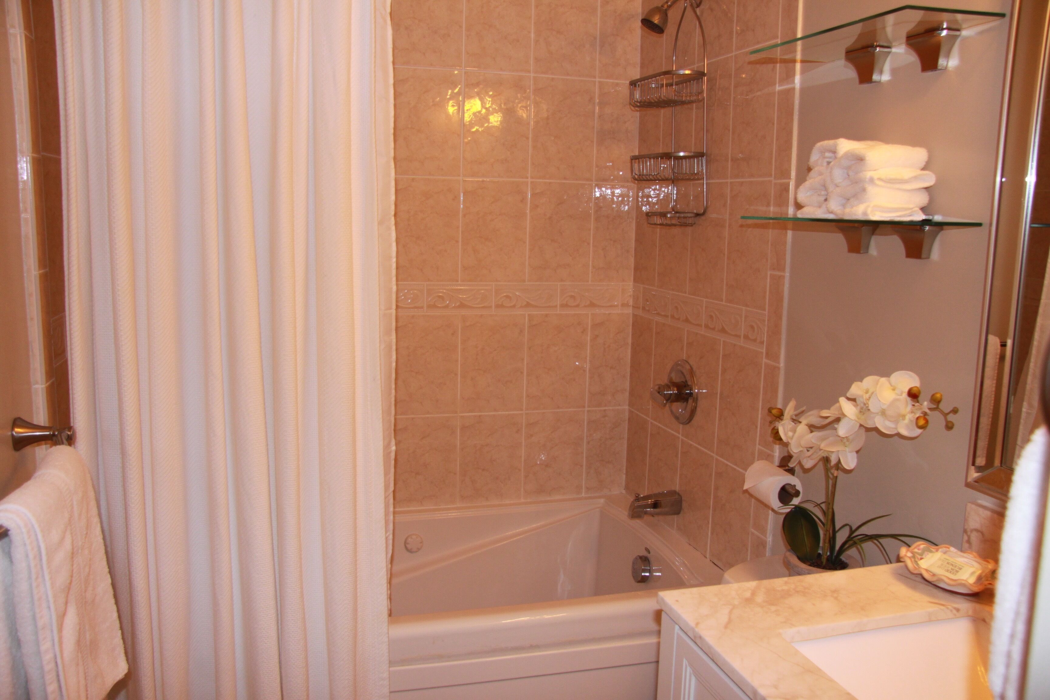 A bathroom with a bathtub, a shower, and a vanity with a mirror.