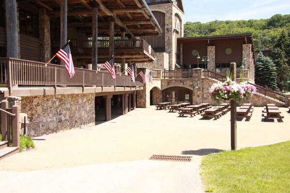 A building with a stone facade, multiple American flags, and outdoor picnic tables.