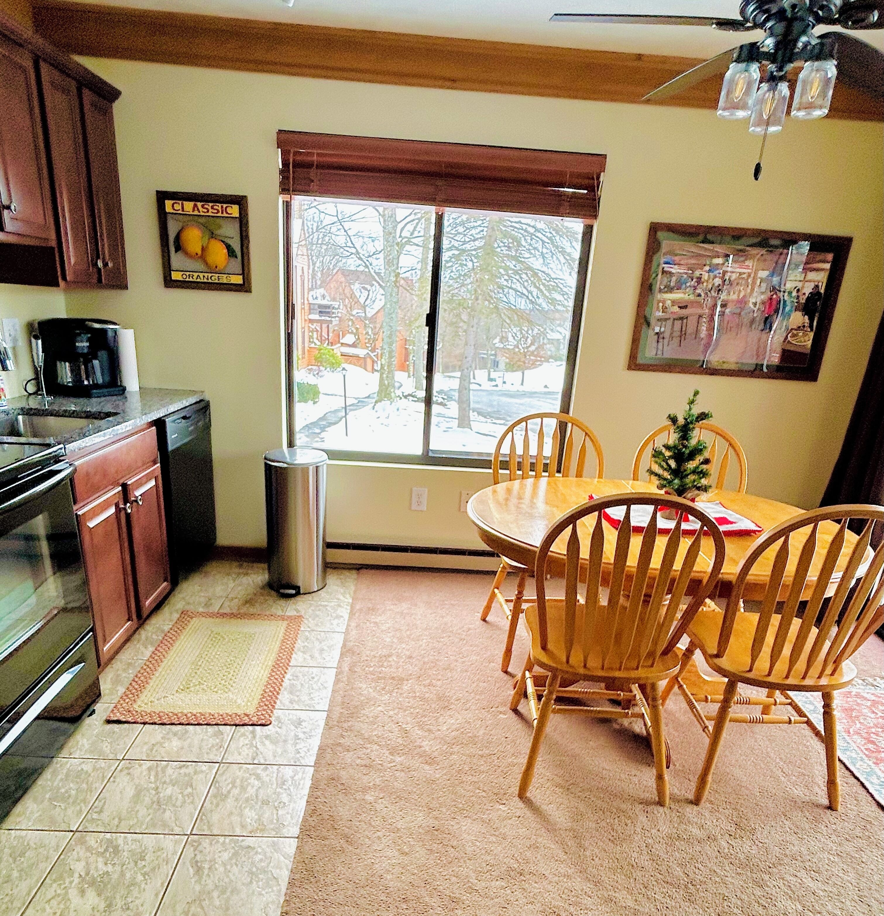 Una cocina con comedor, que incluye armarios, estufa, basurero y ventana con vista al exterior.