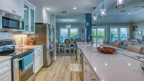 Una cocina moderna con electrodomésticos de acero inoxidable, una isla grande y un comedor con vistas al exterior.