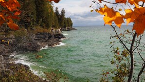 A coastal scene with rocky cliffs and autumn foliage. - Cozy Log Cabin ON THE WATER with the Best Sand Beach in Door County! (Sturgeon Bay)