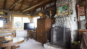 A cozy cabin interior with a stone fireplace, wooden beams, and a television on a wooden stand. - Cozy Log Cabin ON THE WATER with the Best Sand Beach in Door County! (Sturgeon Bay)