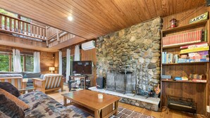 Ein gemütliches Blockhaus-Interieur mit Kamin aus Stein, Holzmöbeln und einer Bücherwand.