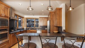 A modern kitchen with wooden cabinets, stainless steel appliances, and a large island with bar stools.