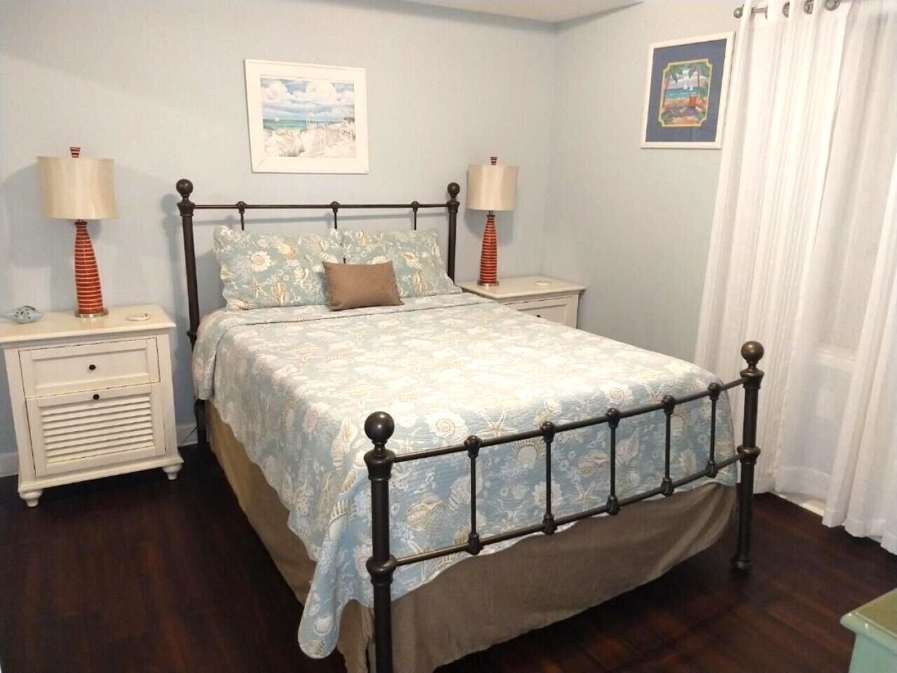 A bedroom with a bed, two bedside tables, and two lamps.