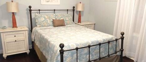 A bedroom with a bed, two bedside tables, and two lamps.