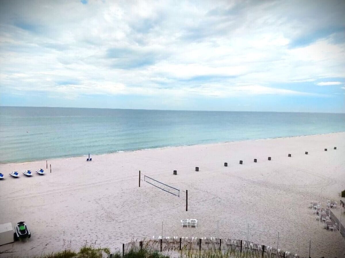 En strand med volleyballnet, både og liggestole.