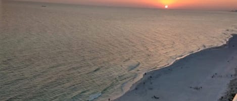 Una playa con gente caminando por la orilla al atardecer.