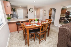 Un coin repas avec une table en bois, des chaises et une cuisine en arrière-plan.