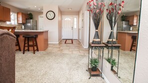 A modern kitchen with wooden cabinets, a stainless steel refrigerator, and a dining area with stools.