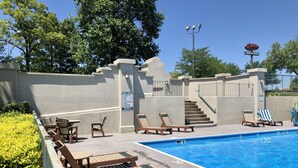 A pool area with lounge chairs, a sign listing pool rules, and a brick oven sign in the background.