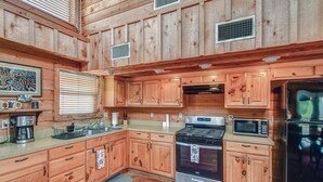 A wooden cabin-style kitchen with a stove, microwave, and refrigerator. - Mata'Zamo cliffside cabin, 1000 acres hiking trails, farm animals, family fun! (Glen Rose)