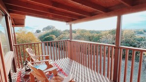 A wooden deck with a view of a forested landscape. - Mata'Zamo cliffside cabin, 1000 acres hiking trails, farm animals, family fun! (Glen Rose)