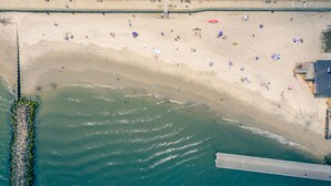Vista aerea di una spiaggia con un molo che si protende verso il mare.