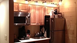 Una cocina compacta con armarios de madera, electrodomésticos de acero inoxidable y un pequeño cubo de basura.