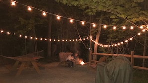 Un espacio al aire libre con luces colgantes, una chimenea y una mesa cubierta.