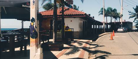 Un restaurante frente al mar con terraza, palmeras y vistas al océano.