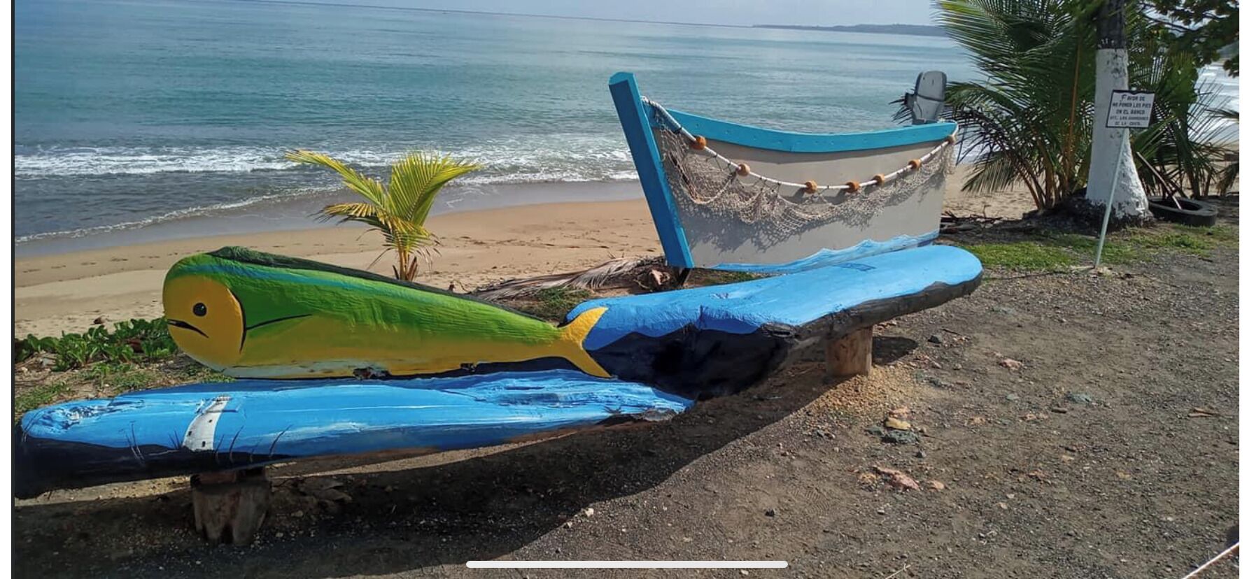 A boat with a green and yellow design on a wooden structure by the beach.