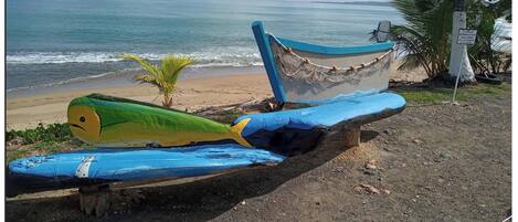 A boat with a green and yellow design on a wooden structure by the beach.