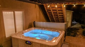 Ein Whirlpool mit Bedienfeld, umgeben von einer Holzdielen-Terrasse und einer Ziegelwand.