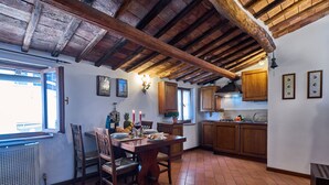 Una cocina rústica con vigas de madera, una mesa de comedor con sillas y un ventanal con vistas.