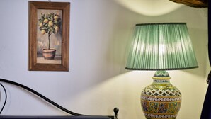 Una cama con cabecera, una mesita de noche con lámpara y un cuadro enmarcado en la pared.