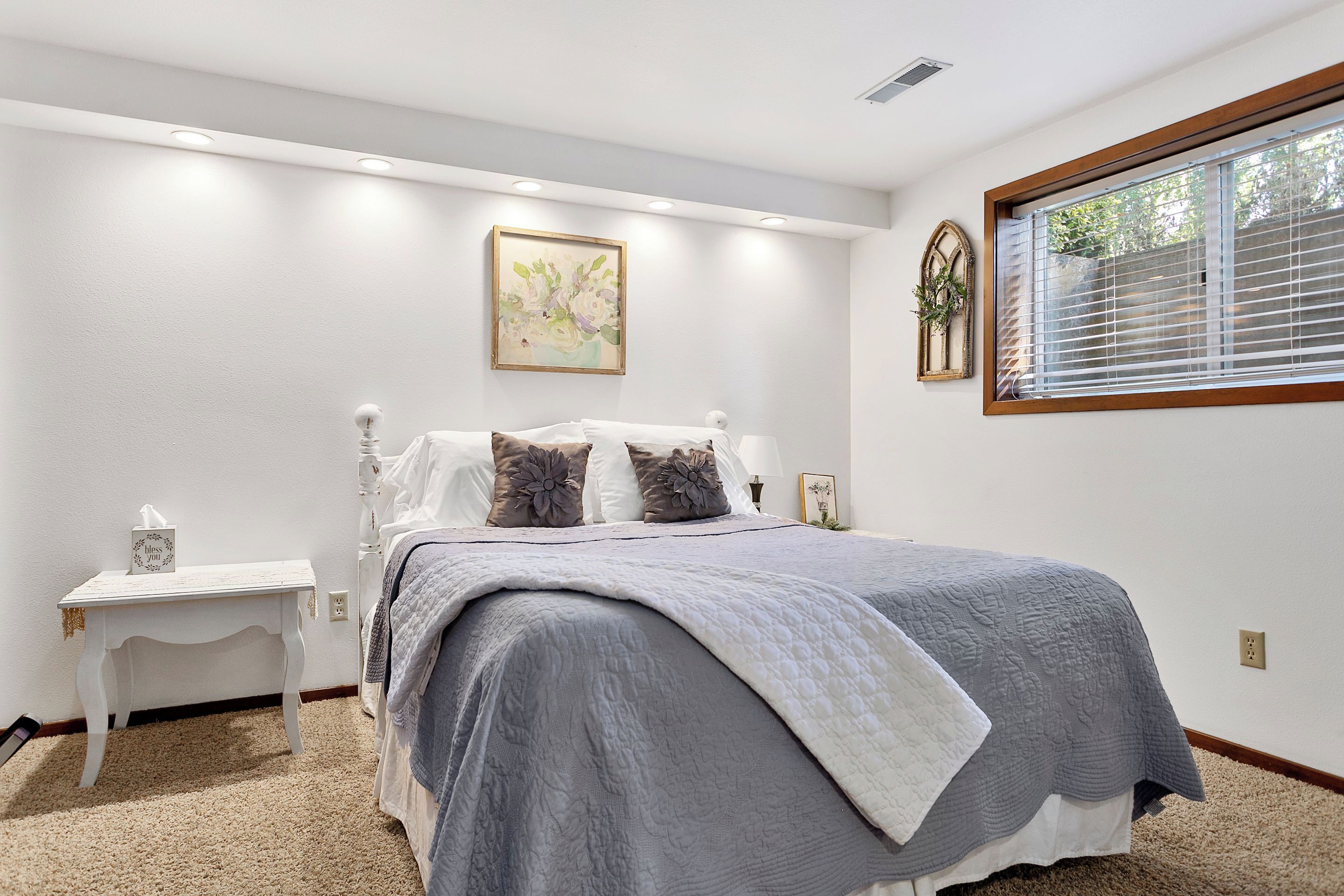 A bedroom with a bed, bedside table, and a window with blinds.