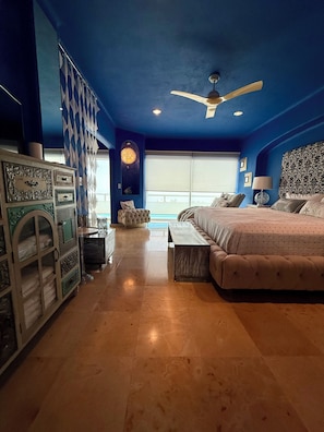 A bedroom with a bed, a ceiling fan, a window, and a dresser.