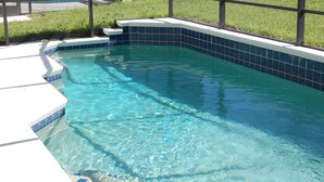 A clear swimming pool with blue tiles and a white border, surrounded by a grassy area and a fence. -  3 miles to Disney, Private 4bed/3bath w/ private pool, game room and club house (Kissimmee)