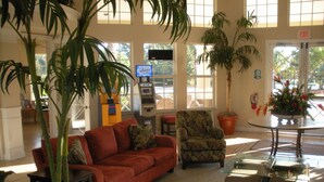A lobby with a red sofa, patterned armchair, and a glass coffee table. -  3 miles to Disney, Private 4bed/3bath w/ private pool, game room and club house (Kissimmee)