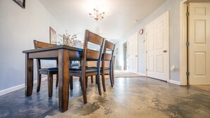 Ein Essbereich mit einem Holztisch und Stühlen, einer Chandelüstere und einem Flur mit Türen.
