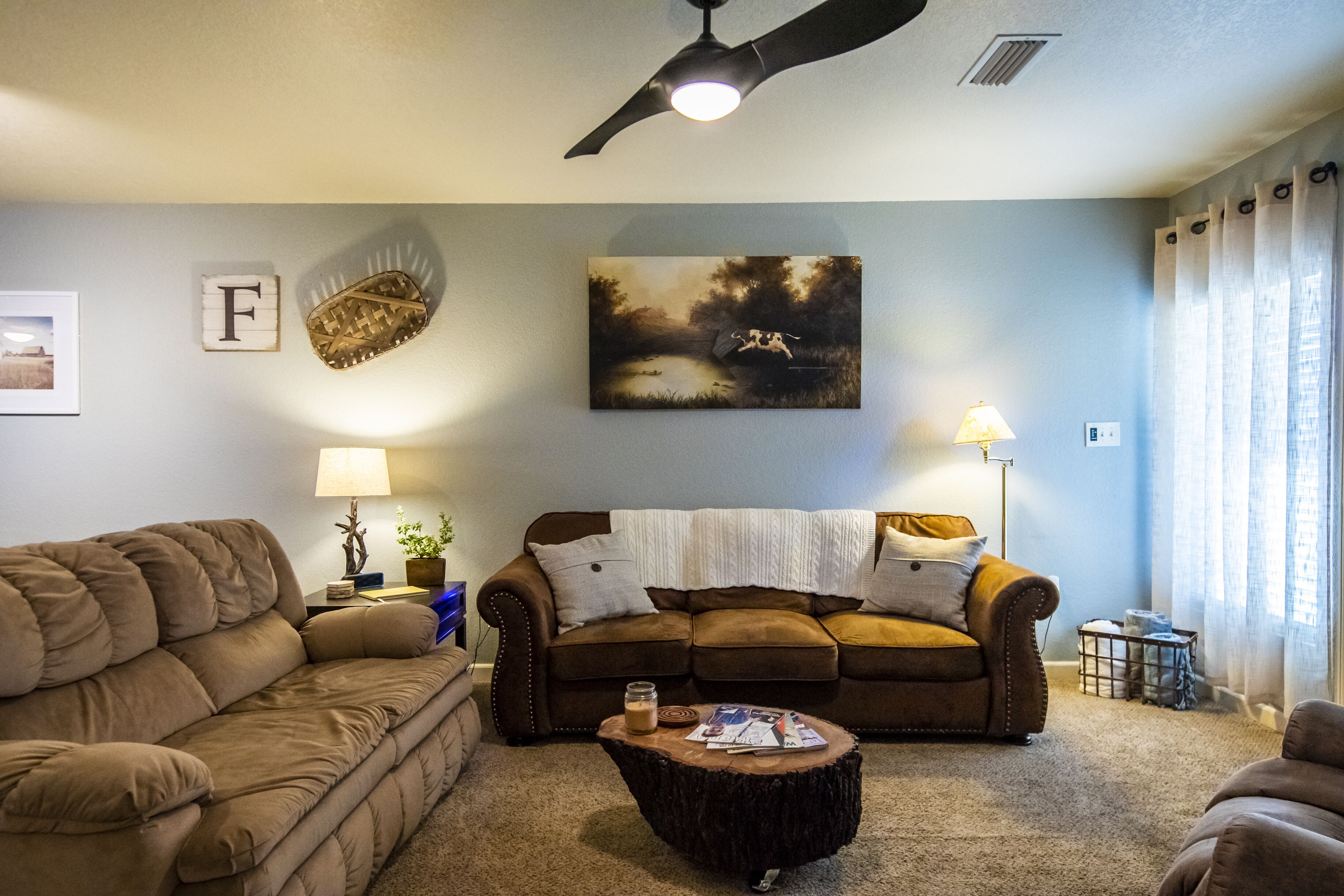 A living room with a brown sofa, a wooden coffee table, and a painting on the wall.