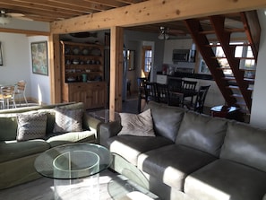 Un salon chaleureux avec un canapé en cuir, une table basse en verre et un coin repas en bois avec des chaises.
