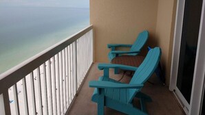A balcony with two turquoise Adirondack chairs, a white railing, and a view of the ocean. - 19th floor with  beach view free beach service and 10% weekly discount (Panama City Beach)