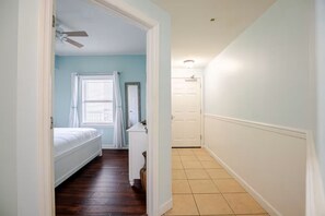 A bedroom with a bed, a dresser, a mirror, and a window with curtains.