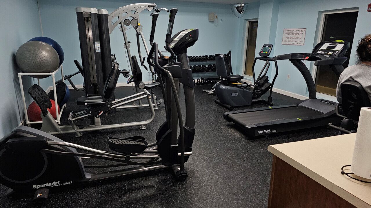Un gimnasio con diversos equipos de ejercicio, incluyendo cintas de correr, elípticas y pesas libres.
