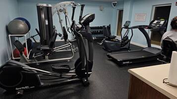 Un gimnasio con diversos equipos de ejercicio, incluyendo cintas de correr, elípticas y pesas libres.