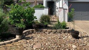 Una casa de dos pisos con fachada blanca, puerta de garaje gris y entrada de adoquines.