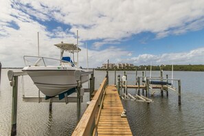 A boat docked at a wooden pier with a clear sky and buildings in the background.