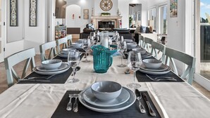 Een eethoek met een lange tafel gedekt voor een maaltijd, stoelen en een decoratief middelpunt.
