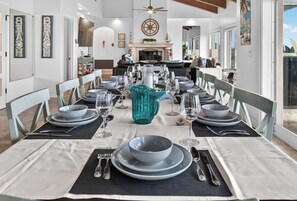Un comedor con una larga mesa dispuesta para una comida, sillas y un centro de mesa decorativo.