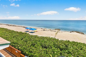 Ein Strand mit blauem Himmel, sandigem Ufer und einem blauen Sonnenschirm.