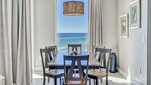 Een eetgedeelte met een tafel en stoelen, een hanglamp en uitzicht op de oceaan.