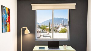 Quarto com escrivaninha, laptop, tablet e pasta.