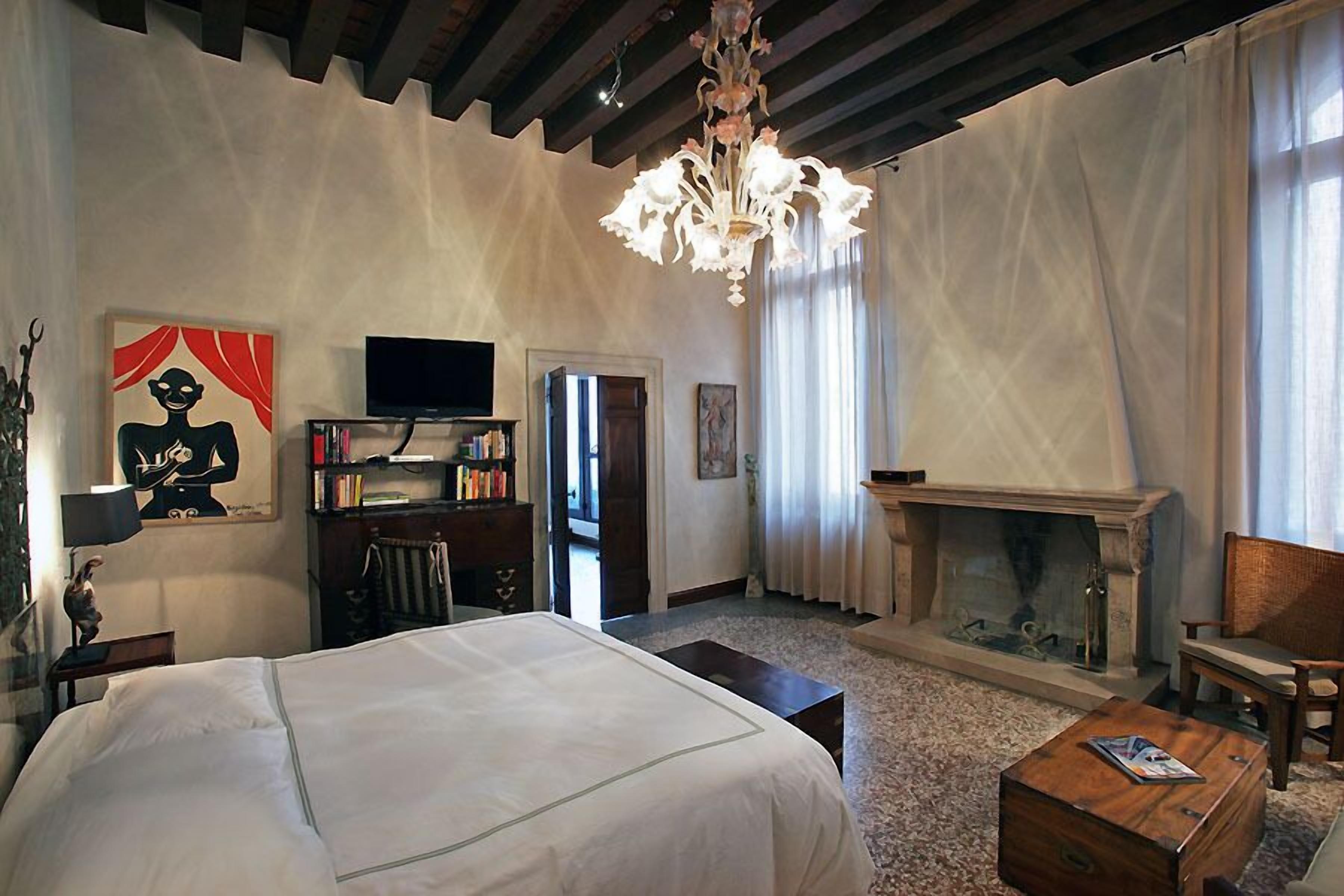 A bedroom with a large bed, a fireplace, a television, and a bookshelf.