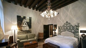 Ein Schlafzimmer mit einem großen Bett, einem Sofa, einem Schreibtisch und einem Bild an der Wand.