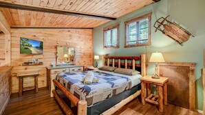 A wooden cabin-style bedroom with a bed, bedside tables, a dresser, a mirror, and a window with shutters. - Camelback,Aquatopia/Camelbeach Waterparks,Pool,Tennis,Jacuzzi,Paintball,Zip-line (Tannersville)