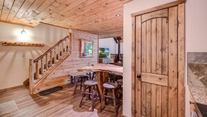 A wooden interior with a staircase, a bar area with stools, and a door. - Camelback,Aquatopia/Camelbeach Waterparks,Pool,Tennis,Jacuzzi,Paintball,Zip-line (Tannersville)