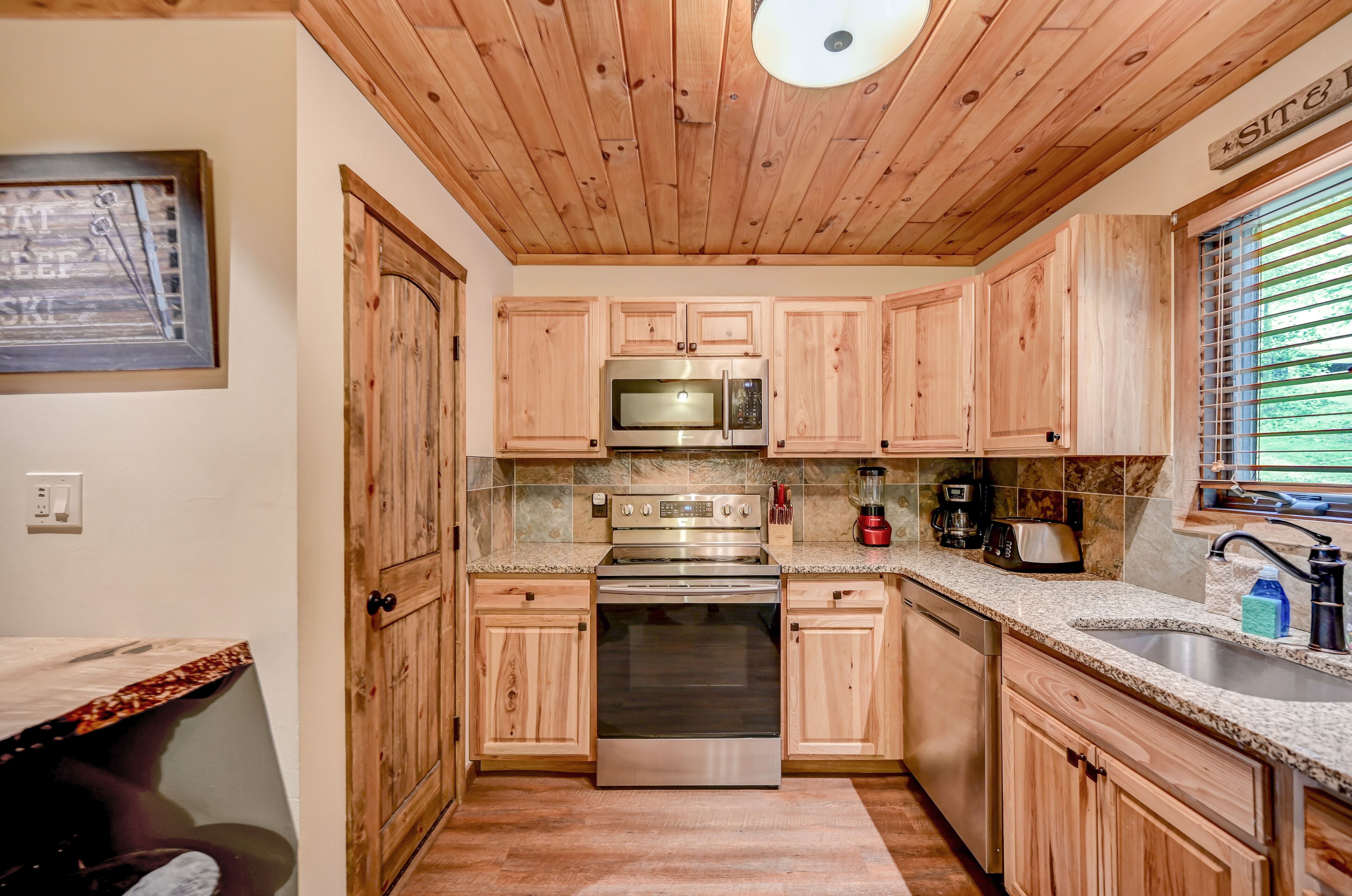 A kitchen with wooden cabinets, stainless steel appliances, and a granite countertop.