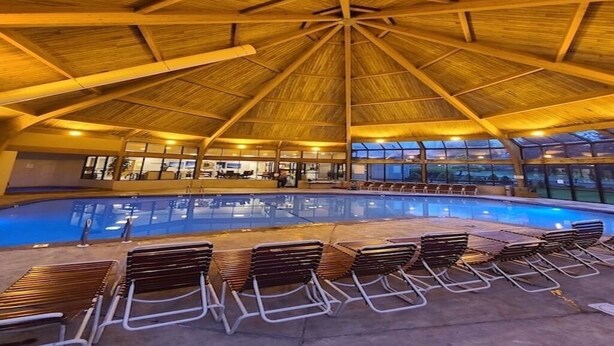 A large indoor swimming pool with a wooden ceiling and lounge chairs around it. - Camelback,Aquatopia/Camelbeach Waterparks,Pool,Tennis,Jacuzzi,Paintball,Zip-line (Tannersville)